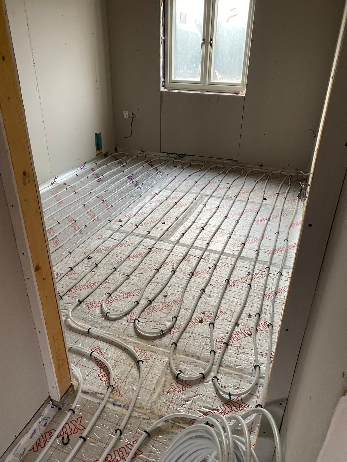 Wet underfloor heating pipework clipped out over insulation before screeding by DBD Builders Ltd