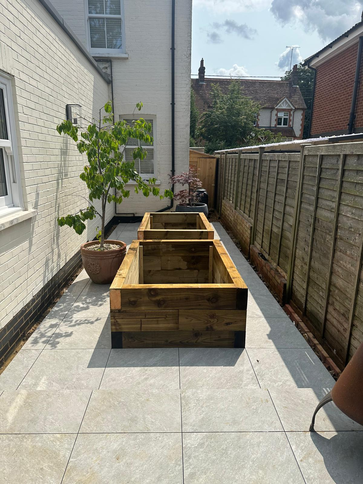 Side garden with large format porcelain paving and timber sleeper planters built by DBD Builders Ltd