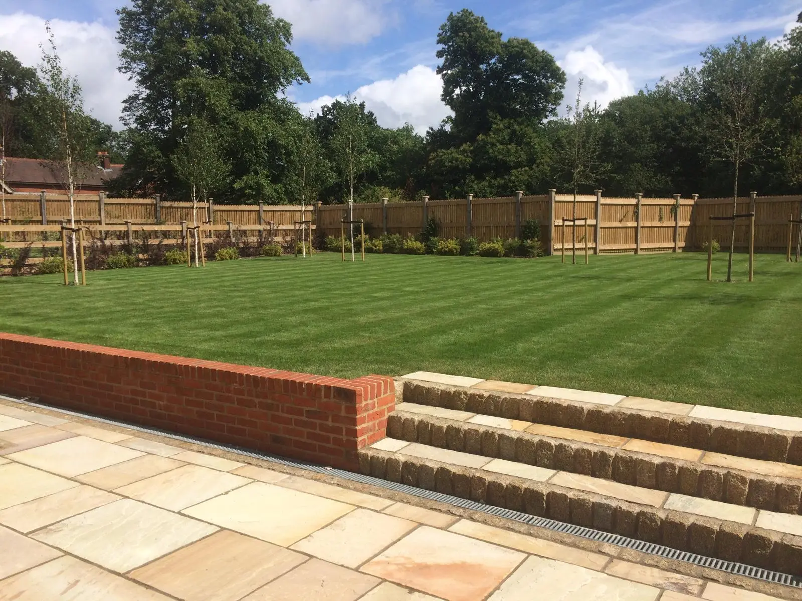 Landscaped rear garden with new lawn, brick retaining wall and Indian sandstone patio by DBD Builders Ltd